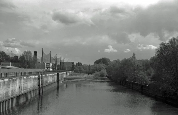 Analog black and white photography of an industrial landscape at a canal.