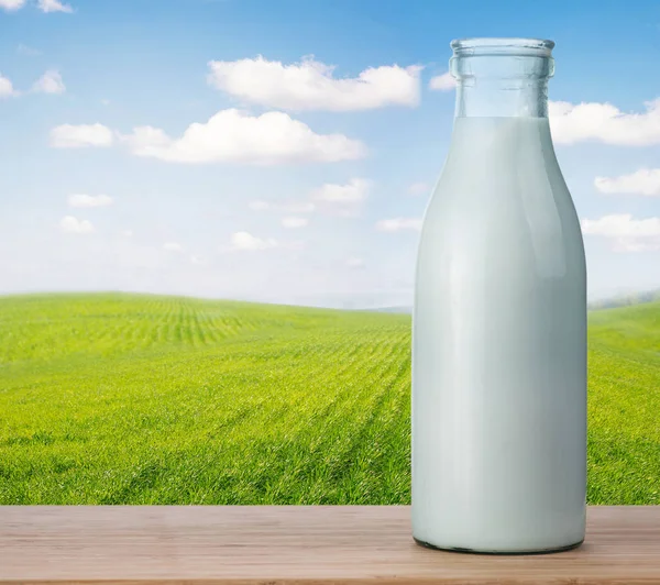 Botella de leche contra el campo verde — Foto de Stock