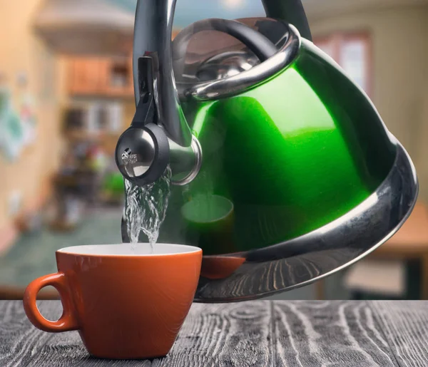 Чайник наливая воду в чашку — стоковое фото