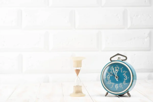 Синий будильник и песочные часы — стоковое фото