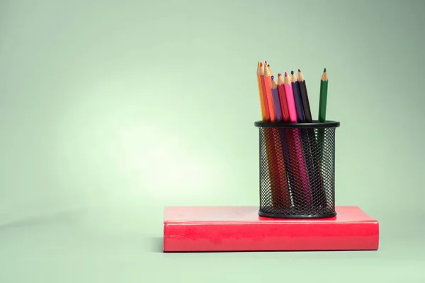 Lápices y libro sobre mesa — Foto de Stock