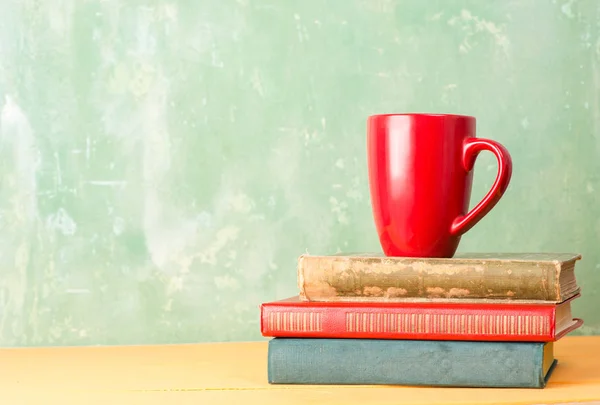Книги и красная чашка на столе — стоковое фото