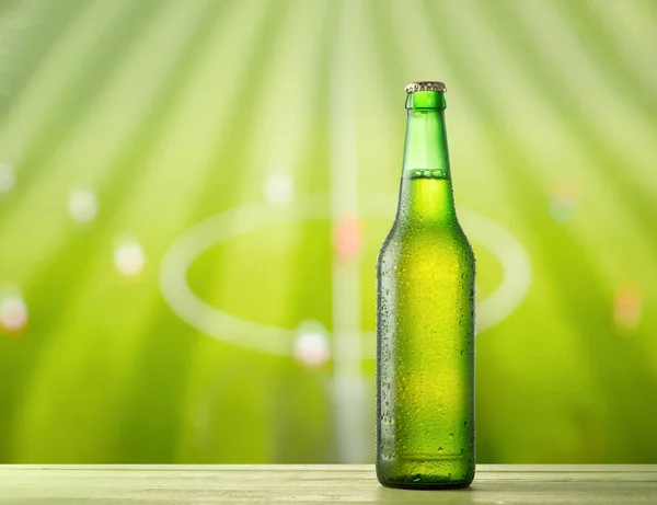 Fles bier en voetbal veld — Stockfoto