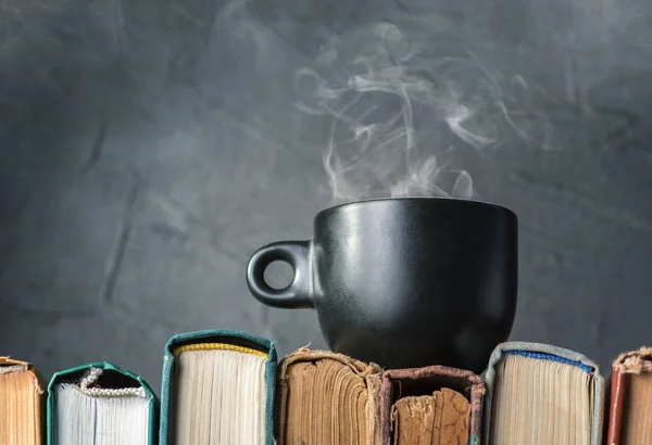 Taza negra de té caliente en libros —  Fotos de Stock