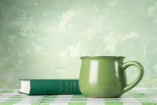Groene boekje en mok op tafel — Stockfoto
