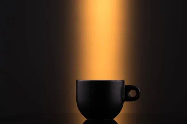 Чорна чашка на помаранчевому фоні — стокове фото