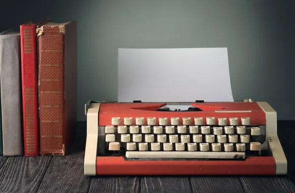 Typewriter and old  books on wooden table