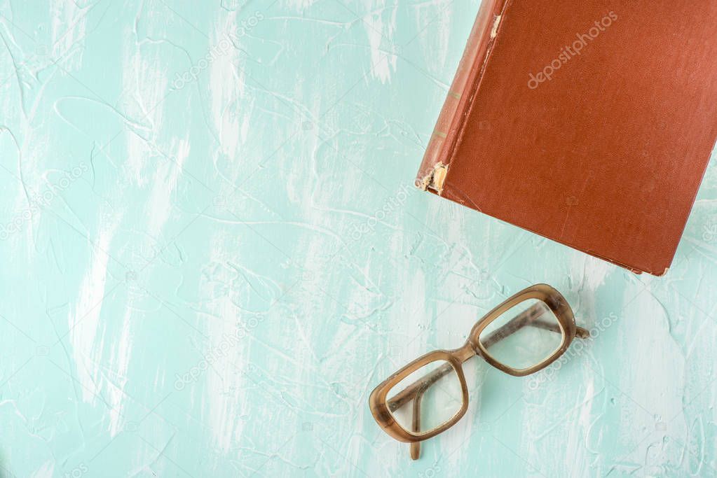 Book and glasses on a blue background, close up