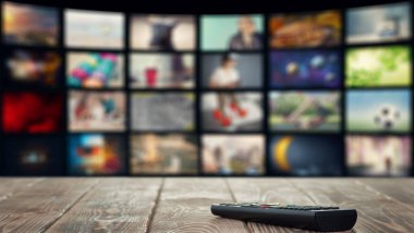 Arka planında televizyon olan bir masanın uzaktan kumandası