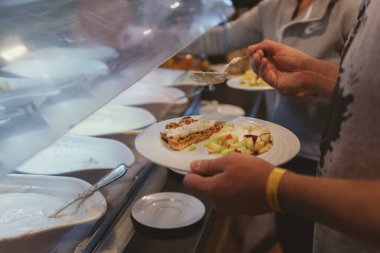 Tabağı olan bir adam tatlıyı self-servis restoranında seçer.