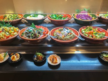 Çeşitli soğuk mezeler ve salatalarla dolu bir büfe.