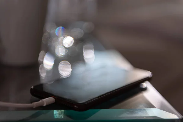 ブラックスマートフォンはガラスのテーブルを充電している — ストック写真