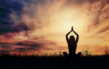 Gün batımında yoga yapan kadın.