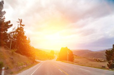 Manzaranın içinden geçen yol. Yol ve araba yolculuğu manzaralı ve günbatımlı. Yol seyahati kavramı. Araba yolculuğu maceraları..