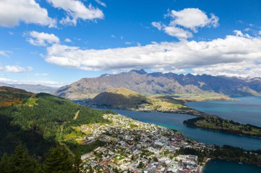 Aydınlatılmış tepeleri olan yüksek kayaları olan güzel bir manzara, dağ gölündeki taşlar, yansıma, mavi gökyüzü ve gün doğumunda sarı güneş ışığı. Tekapo, Queenstown, Wanaka.