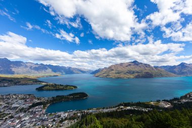 Aydınlatılmış tepeleri olan yüksek kayaları olan güzel bir manzara, dağ gölündeki taşlar, yansıma, mavi gökyüzü ve gün doğumunda sarı güneş ışığı. Tekapo, Queenstown, Wanaka.