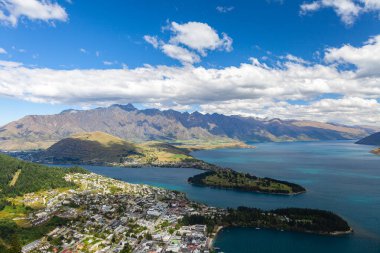 Aydınlatılmış tepeleri olan yüksek kayaları olan güzel bir manzara, dağ gölündeki taşlar, yansıma, mavi gökyüzü ve gün doğumunda sarı güneş ışığı. Tekapo, Queenstown, Wanaka.