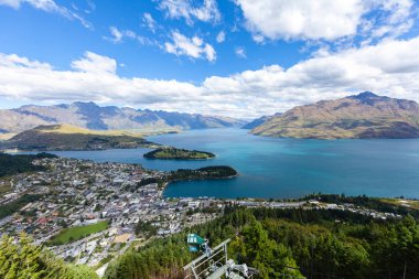 Aydınlatılmış tepeleri olan yüksek kayaları olan güzel bir manzara, dağ gölündeki taşlar, yansıma, mavi gökyüzü ve gün doğumunda sarı güneş ışığı. Tekapo, Queenstown, Wanaka.