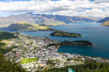 Aydınlatılmış tepeleri olan yüksek kayaları olan güzel bir manzara, dağ gölündeki taşlar, yansıma, mavi gökyüzü ve gün doğumunda sarı güneş ışığı. Tekapo, Queenstown, Wanaka.