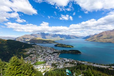 Aydınlatılmış tepeleri olan yüksek kayaları olan güzel bir manzara, dağ gölündeki taşlar, yansıma, mavi gökyüzü ve gün doğumunda sarı güneş ışığı. Tekapo, Queenstown, Wanaka.
