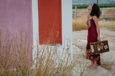 Bavullu ve kırmızı elbiseli bir kadın.