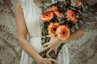 Bir kadının kollarında bir buket gerbera.
