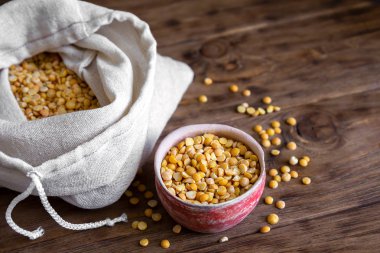 Kil bir fincanda ve ahşap bir masada yeşil bezelye dilimleri..