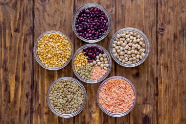 Ahşap arka planda çeşitli mercimek ve fasulyeler.