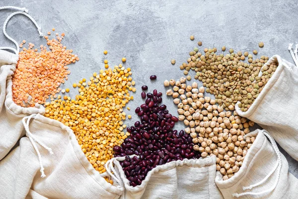 Various legumes in eco bag on gray background