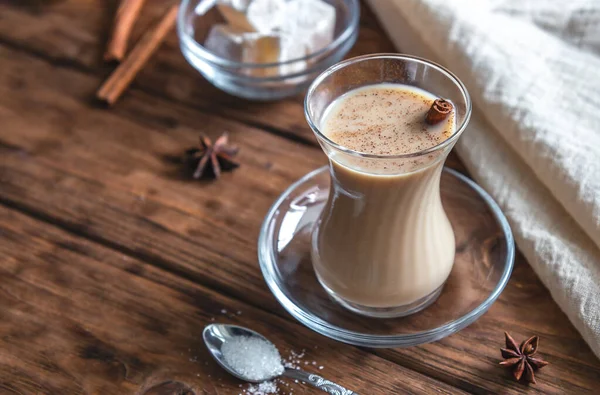 Indischer Tee mit Gewürzen und Milch auf einem hölzernen Hintergrund. masala chai — Stockfoto