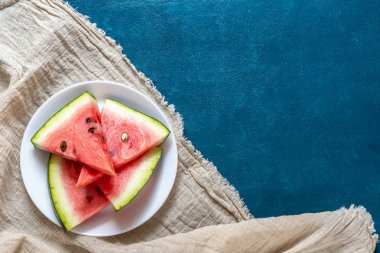 Mavi arkaplanda dilimlenmiş karpuz.