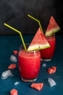 Mavi bir masada şeffaf bardakta iki karpuz suyu.