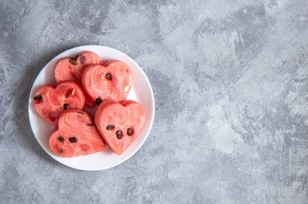 Wassermelonenherzen auf einem Teller auf grauem Hintergrund — Stockfoto