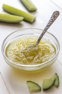 Şeffaf bir kasede salatalık reçeli ve beyaz bir arka planda kaşık.