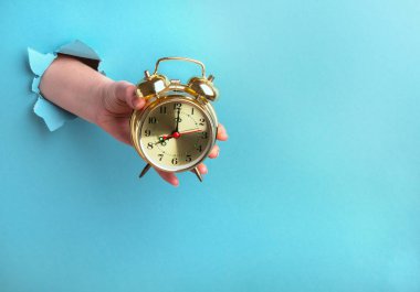 Çalar saat, mavi bir arka planda, zaman kavramına sahip bir kadın elinde.