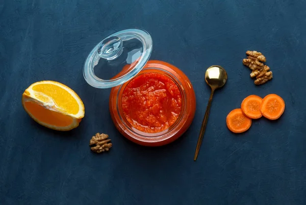 A jar of carrot jam and orange on a dark blue background — Stock Photo, Image