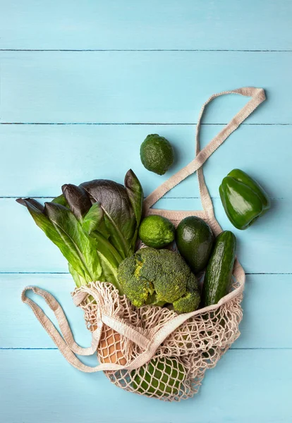 Grünes Gemüse und Obst in einer wiederverwendbaren Saitentüte auf hellblauem Hintergrund — Stockfoto