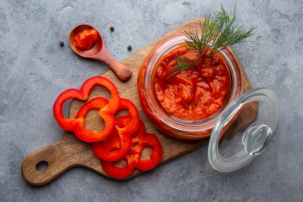 Glasgefäß mit Ajvar, Lutenitza auf grauem Hintergrund — Stockfoto