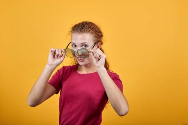 Güneş gözlüklü güzel kadın izole arka planda duruyor ve gülümsüyor..