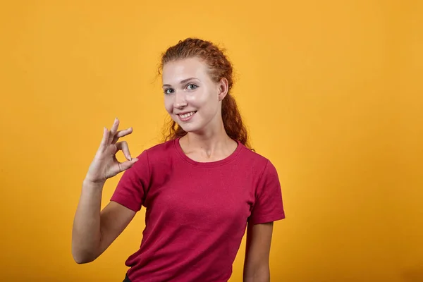 Chica feliz sonriendo, sosteniendo una mano hacia arriba y mostrando el gesto de la mano bien . —  Fotos de Stock