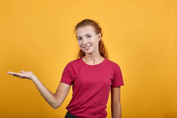 Hermosa mujer europea sobre la pared de luz que muestra un producto con su ambas manos . —  Fotos de Stock