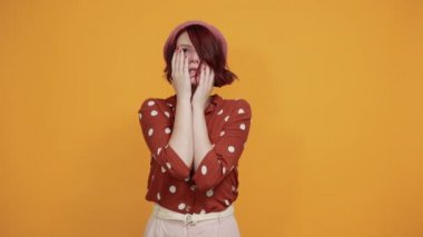 Yorgun, küçük, güzel bir kadın sıkılmış görünüyor. Yarı yüzünü, göz ve ağzını eliyle kapatıyor.