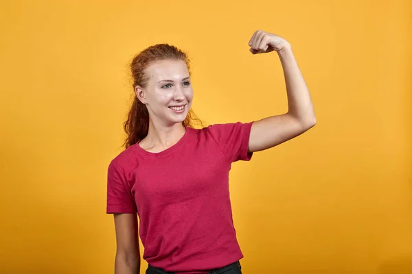 Mujer joven y sonriente mostrando su fuerza con la ayuda de la mano derecha . —  Fotos de Stock