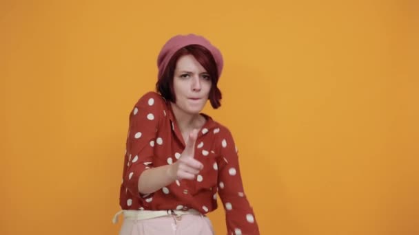 Ung rolig kvinna pekar på framsidan och ler på isolerad gul bakgrund — Stockvideo