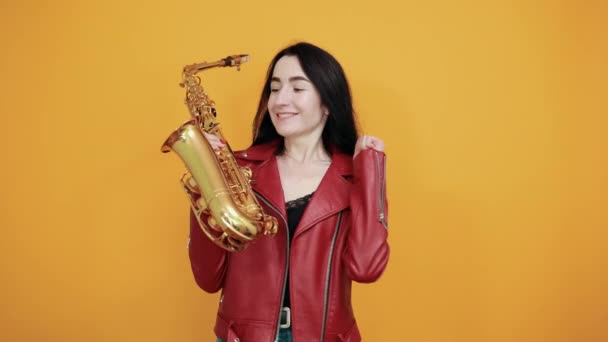 Щаслива молода жінка стискає кулаки, як переможець, тримаючи саксофон, кажучи "так" — стокове відео