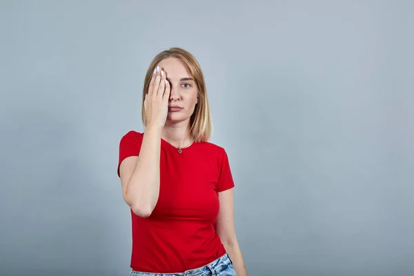 Belle jeune femme portant une chemise rouge se cachant, les yeux couverts de paume des mains — Photo