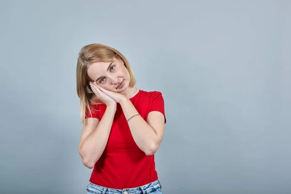 Jeune femme dormir avec les mains pliées sous la joue isolé sur le mur gris — Photo