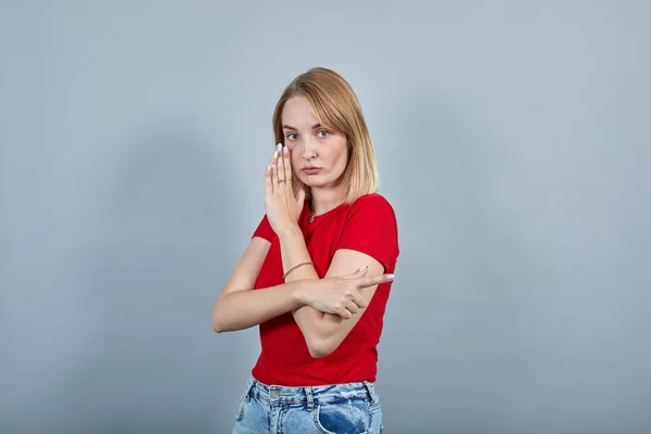 Jovem mulher conta segredo com gesto de mão, apontando dedo indicador de lado — Fotografia de Stock