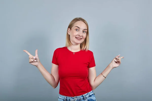 Νεαρή κοπέλα με κόκκινο casual πουκάμισο που δείχνει τα δάχτυλα του δείκτη στην άκρη, κοιτάζοντας κάμερα — Φωτογραφία Αρχείου