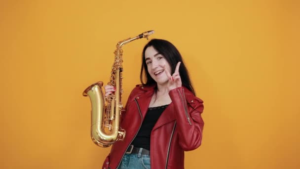 Smiling woman over isolated orange wall studio portrait. Showing victory sign — Stock Video